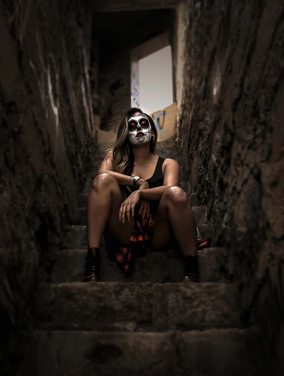people woman wearing skull face paint sitting on stairs person