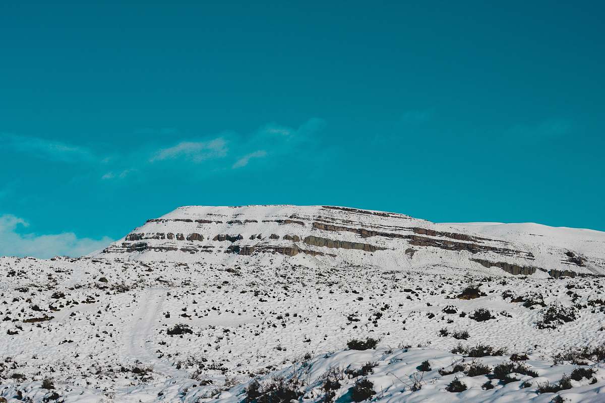 crest mountain covered with snow under green sky mountain range