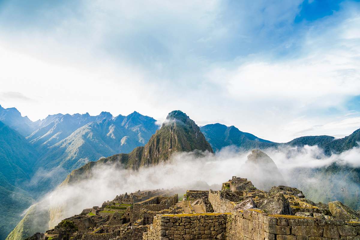 outdoors photo of ruins beside wall covering fogs peru