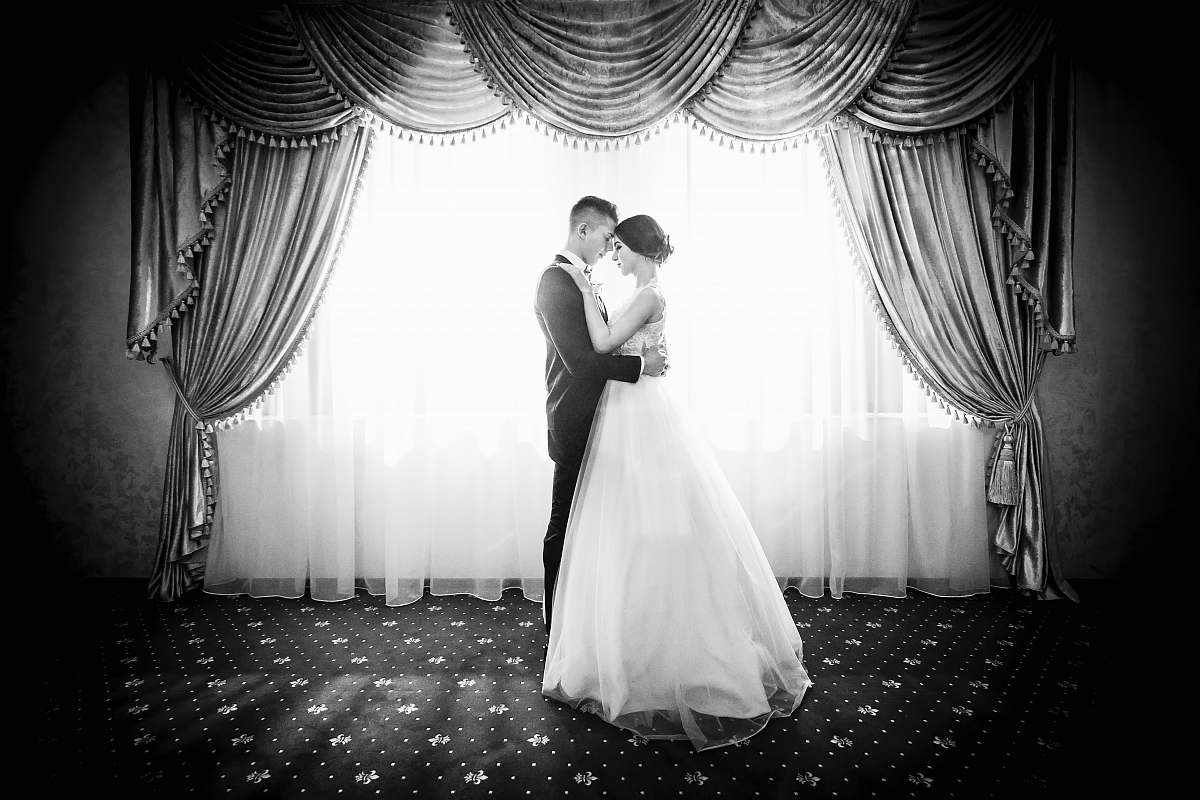 black-and-white grayscale photography of couple facing in front curtain wedding