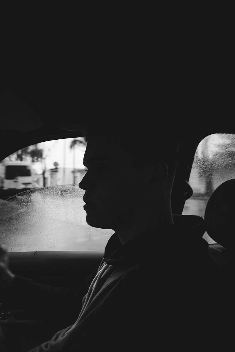human grayscale photography of man inside car black-and-white