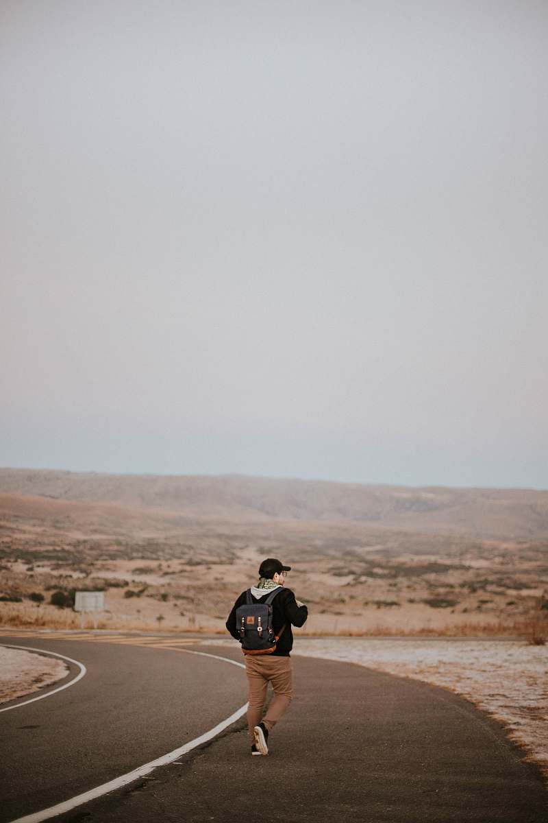 human man walking in middle of asphalt road people