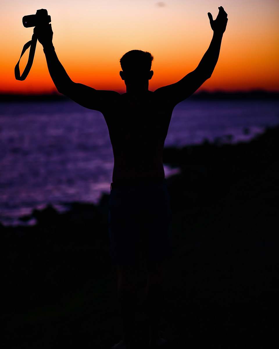 sunset person holding DSLR camera silhouette