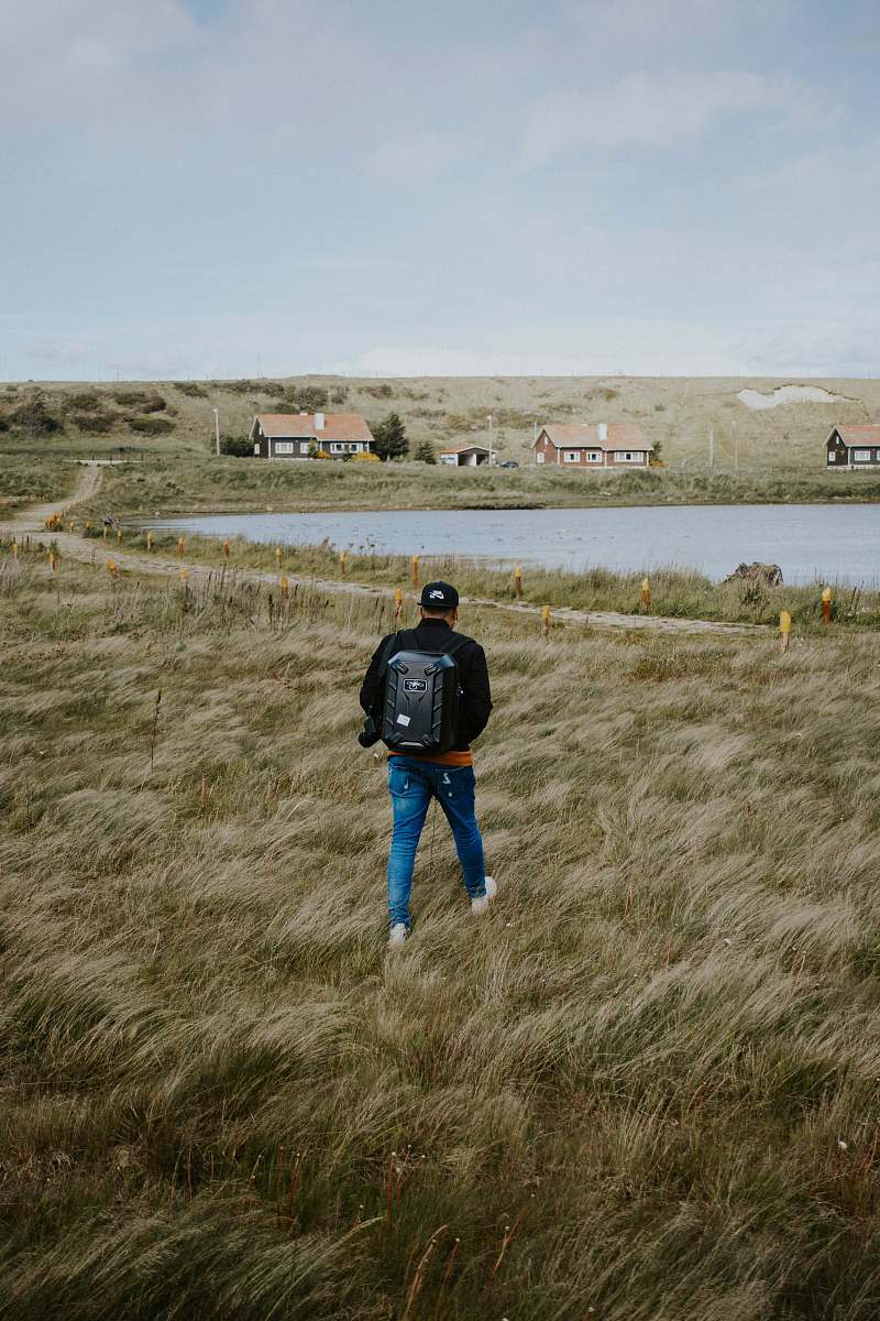 human person wearing blue denim skinny jeans and black jacket walking on the grass people