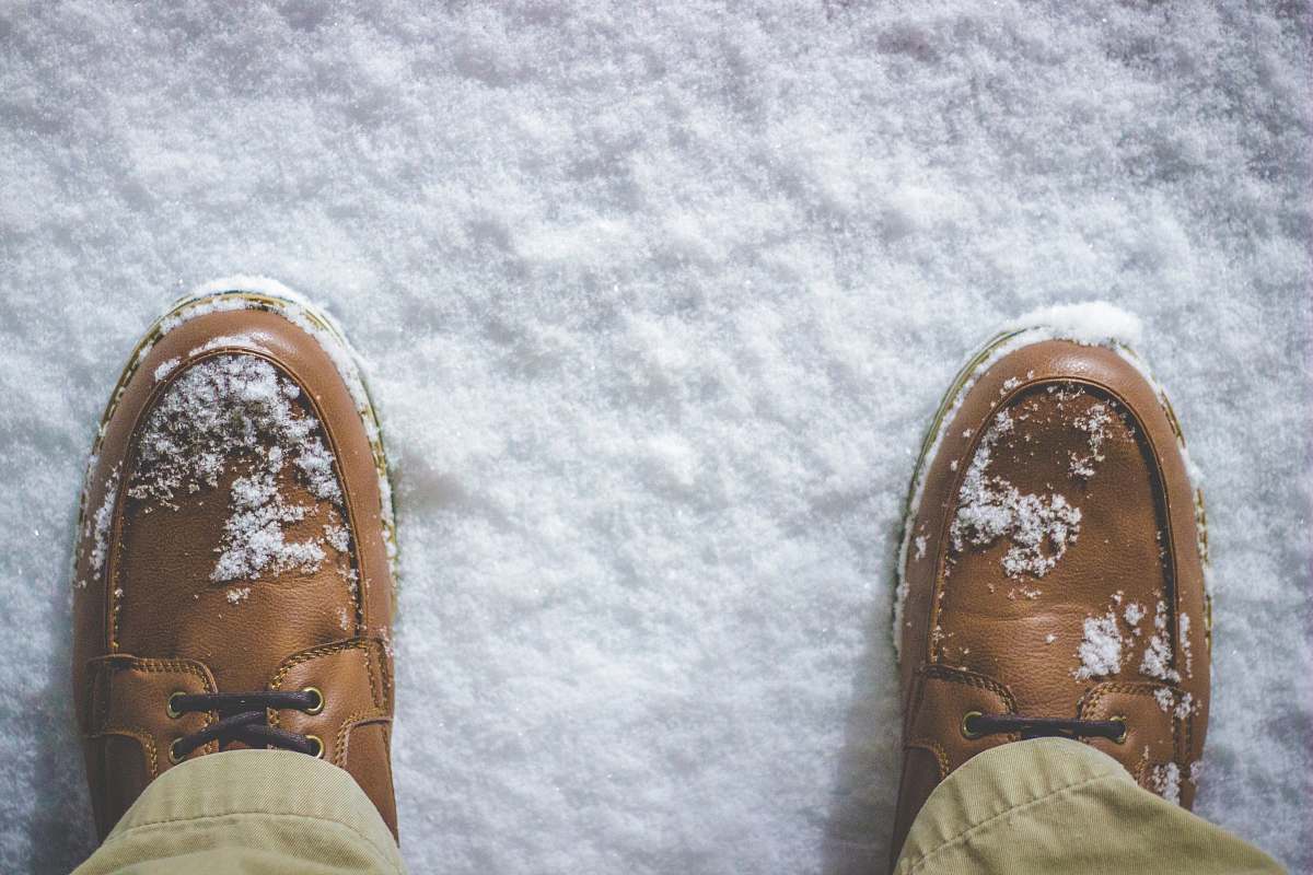 shoe top view photography of person standing on snow covered field feet