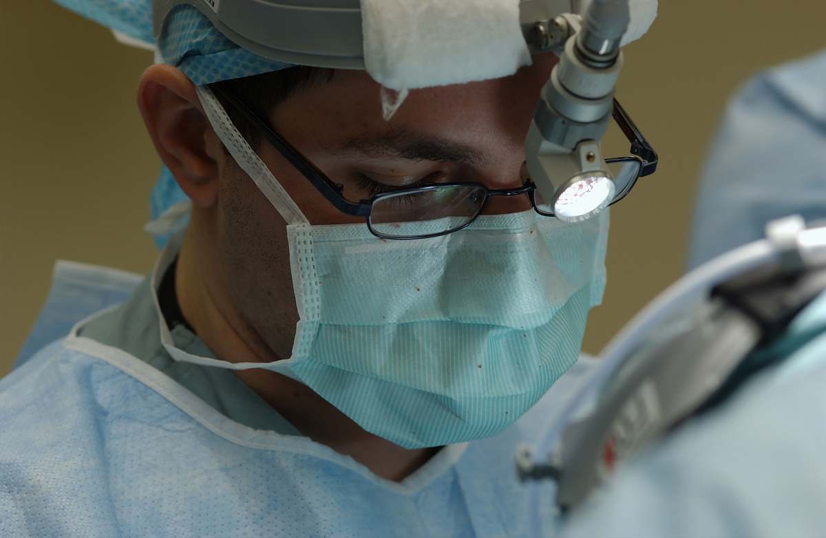surgeon man in blue and white collared shirt wearing green face mask hospital