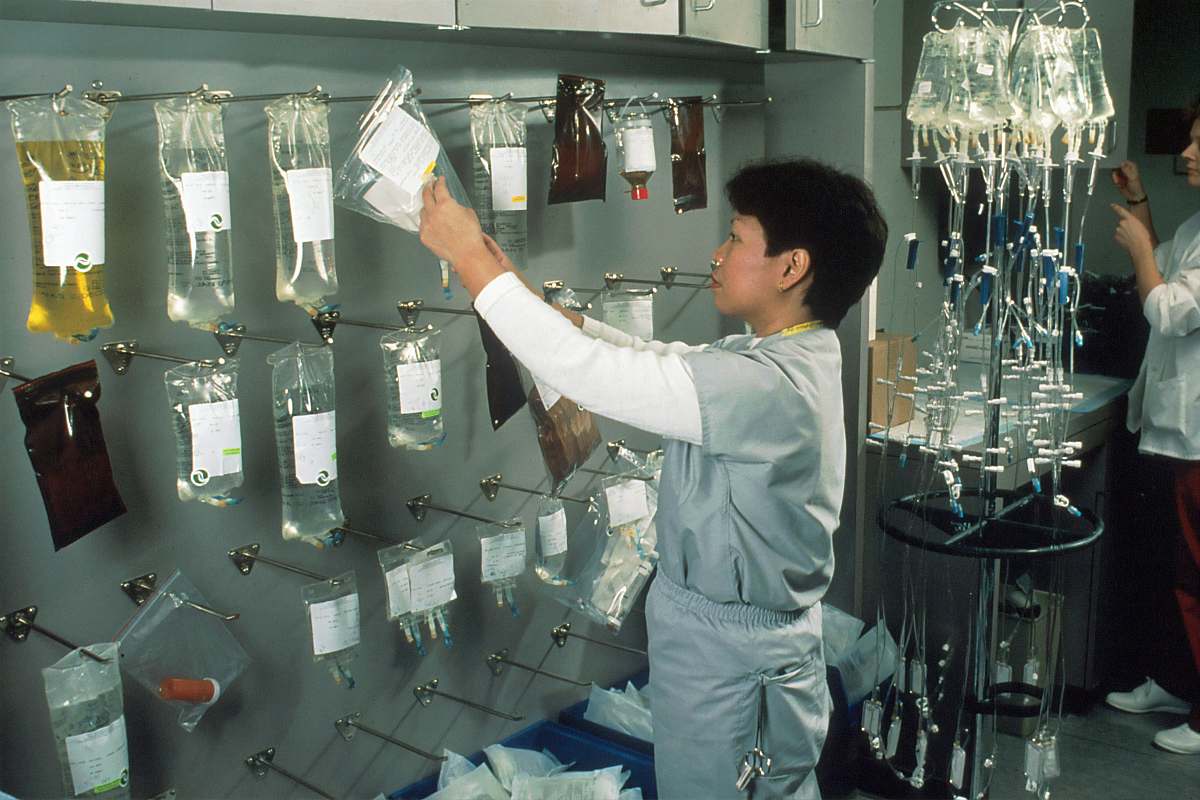 person man in white long sleeve shirt pouring water on clear glass bottles clinic