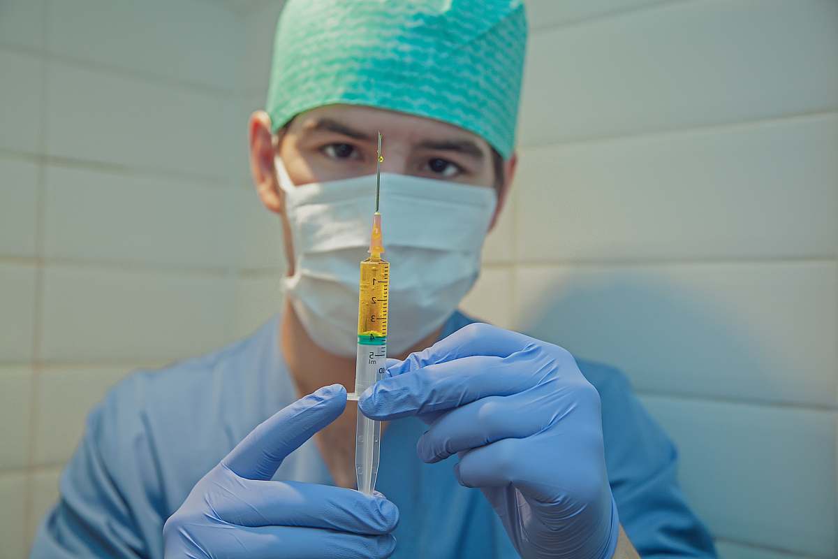 person person in blue knit cap holding clear glass tube surgeon