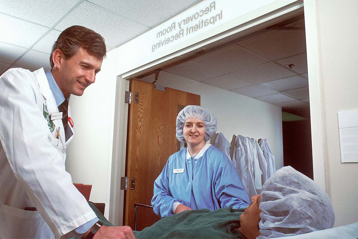 person woman in blue scrub suit standing beside woman in white robe clinic