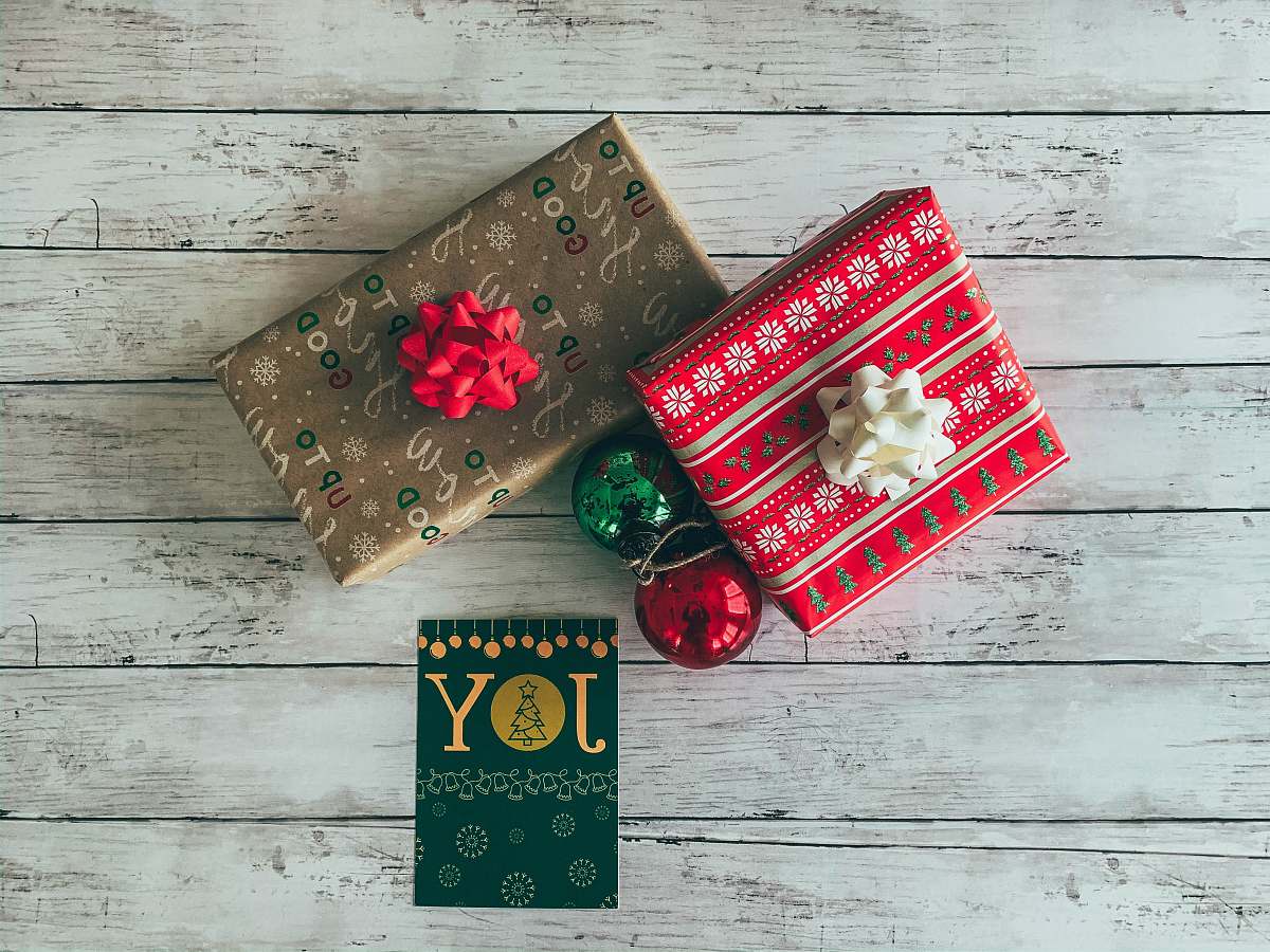 handbag gift boxes beside Joy card and baubles on white surface purse