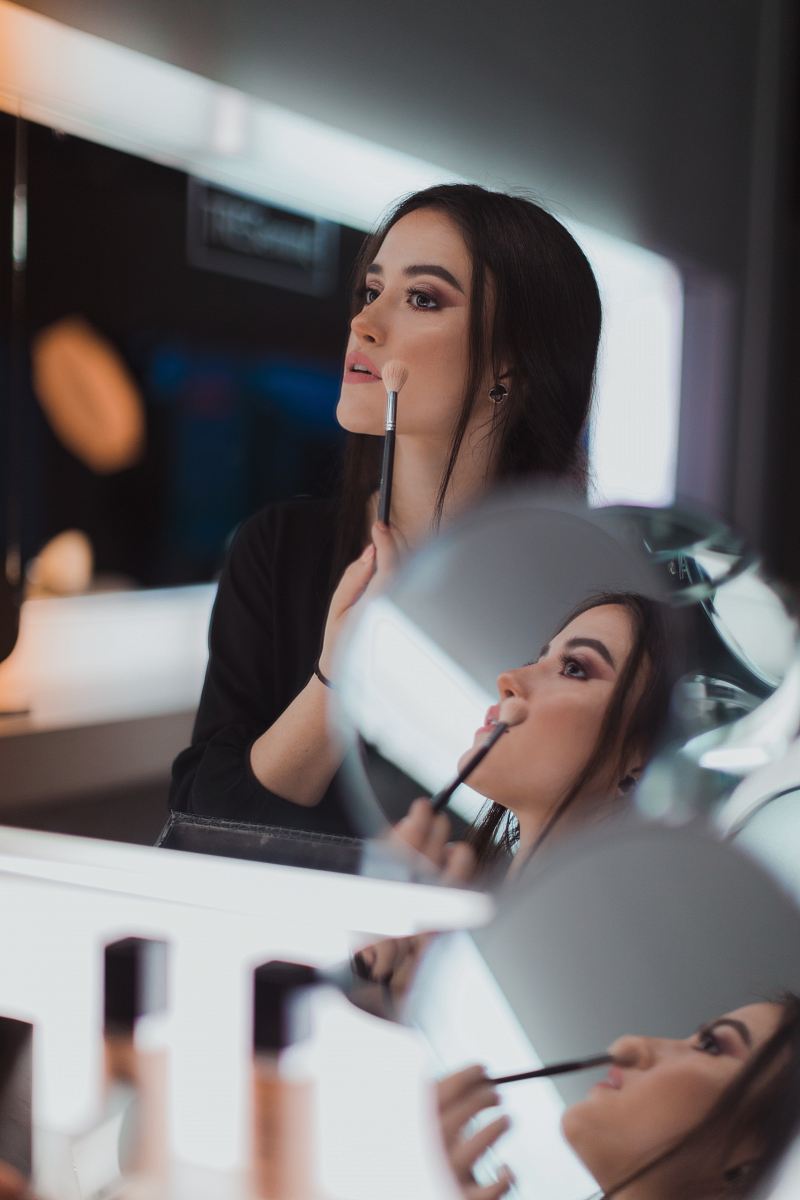 shallow focus photography of woman doing makeup