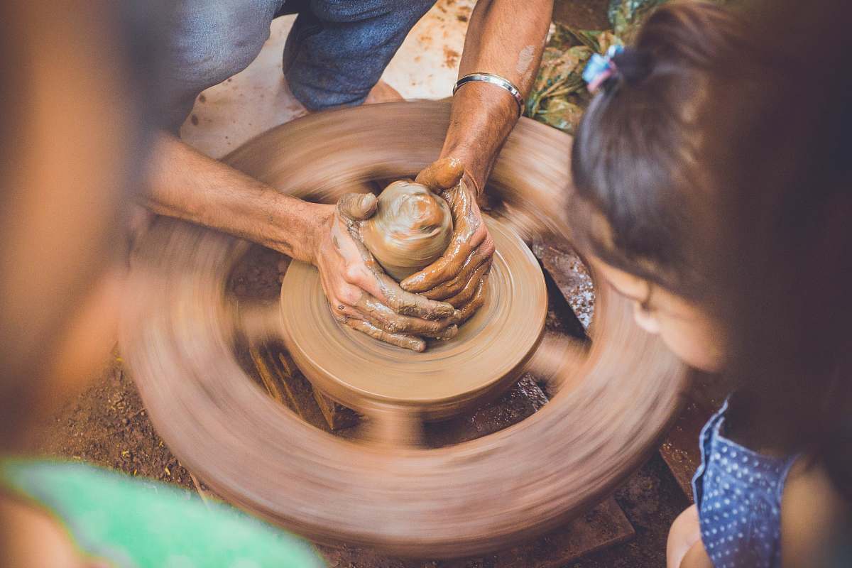 person molding clay while children are watching at daytime 