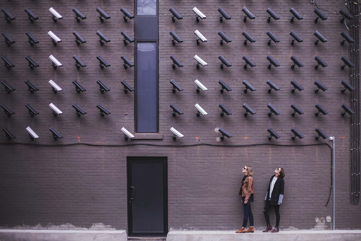 two women facing security camera above mounted on structure 