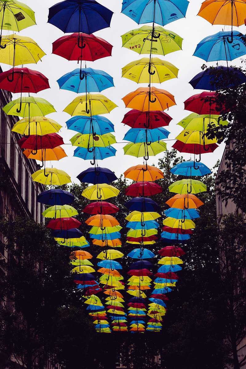 canopy umbrellas hanged in between two white buildings at daytime umbrella