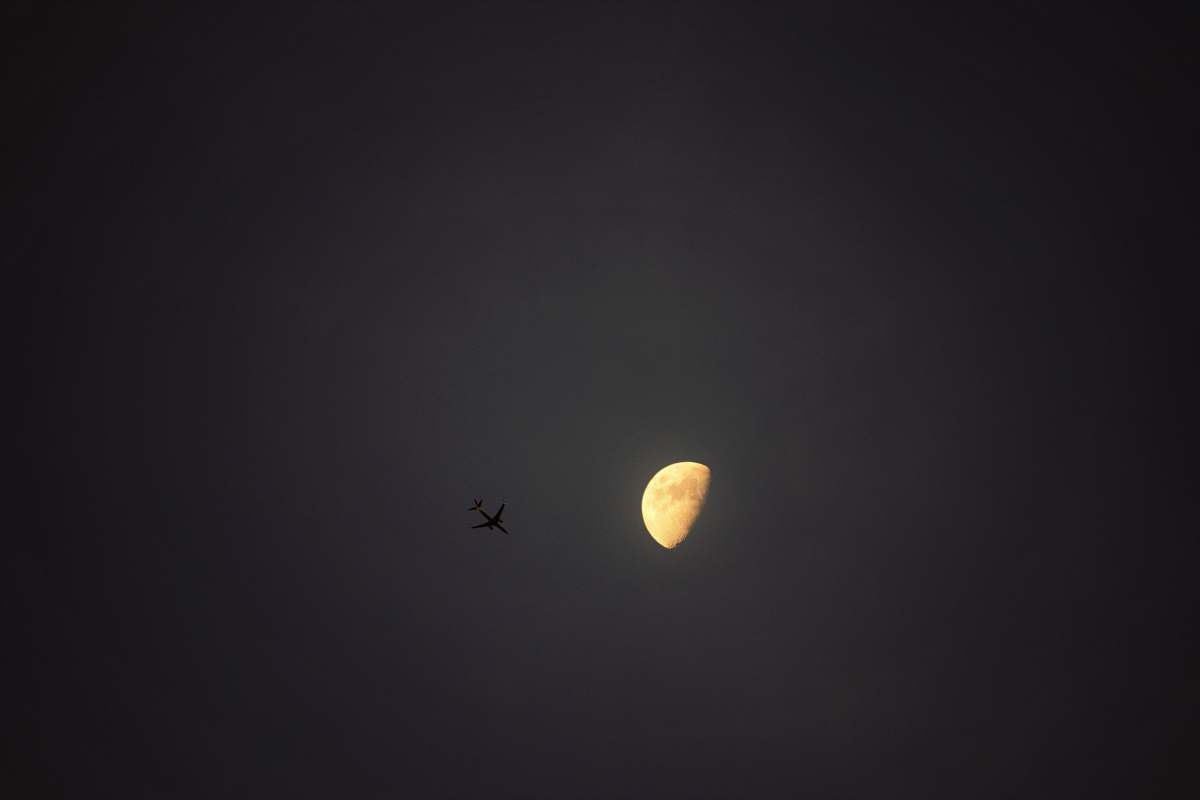 beige silhouette of airplane under half moon during nighttime purple