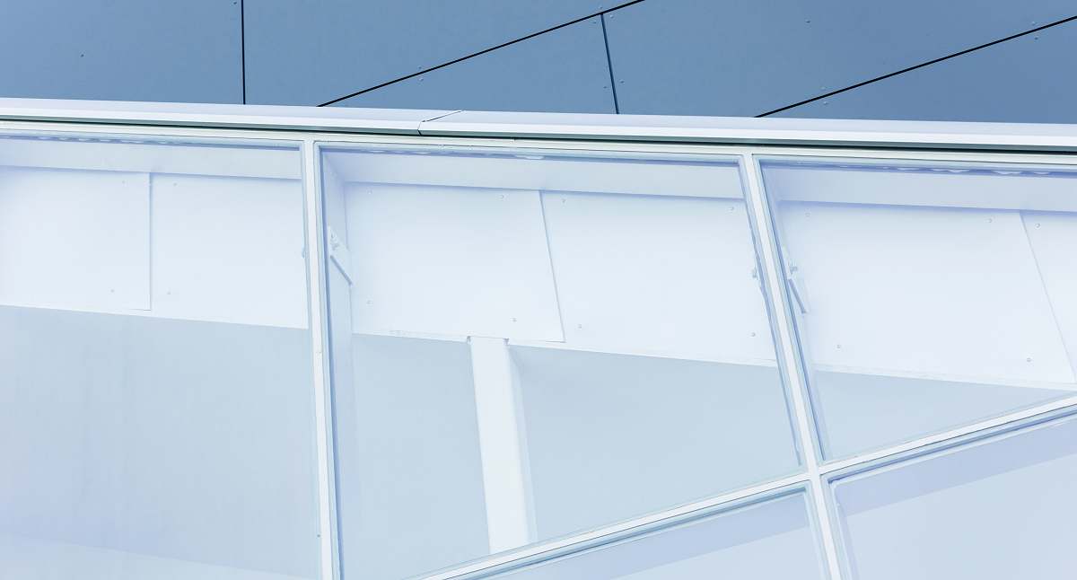 window A close view of a building with dark exterior and large, white-framed white windows cutting across at an angle architectural detail