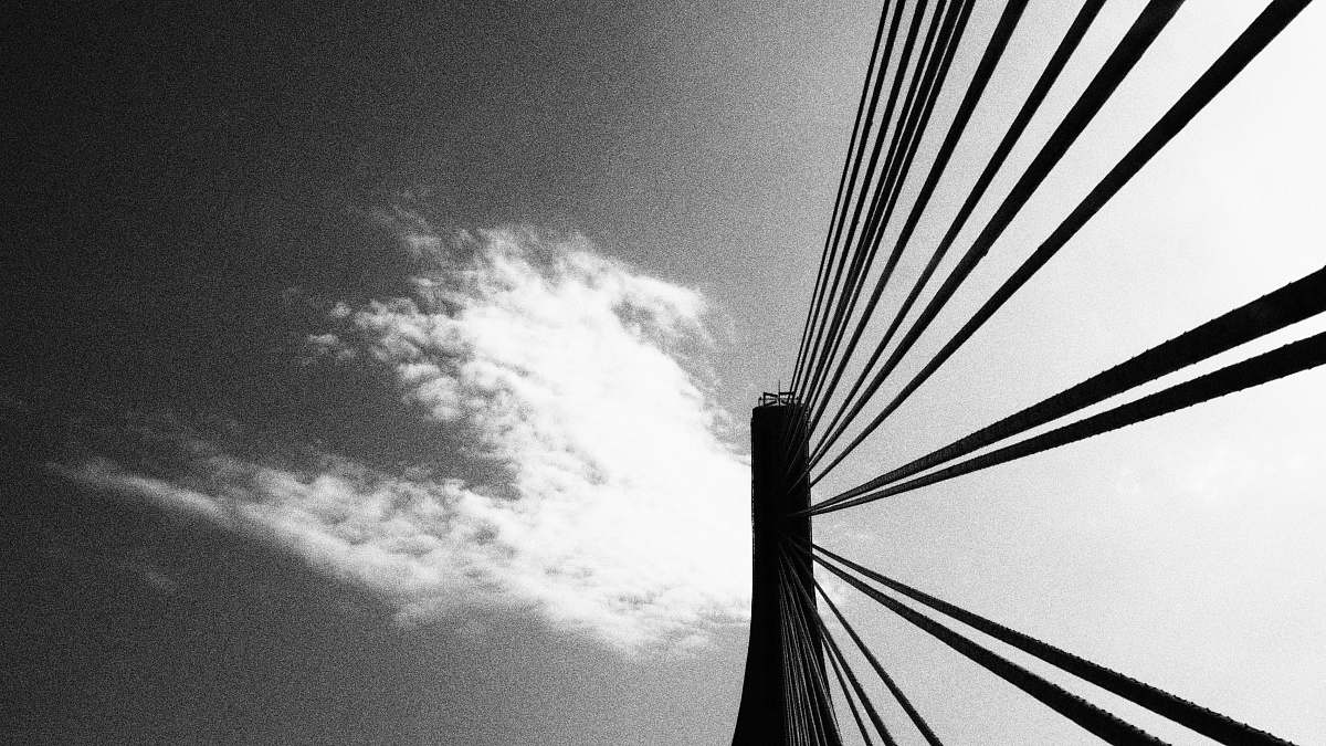 black-and-white low angle photography of bridge wire under clouds bridge