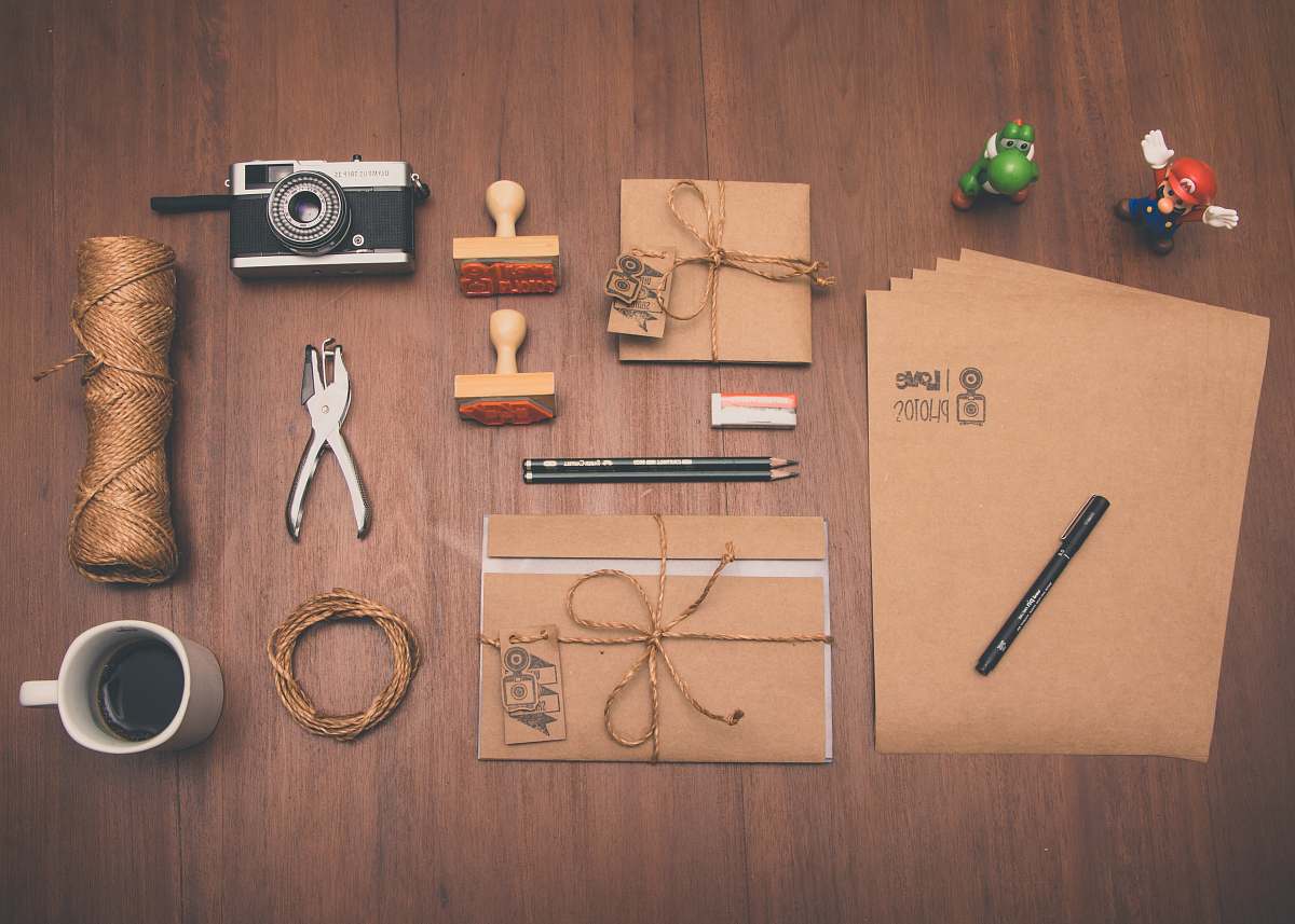 coffee flatlay photograph of brown printer paper, mug, pencil, and camera flat lay