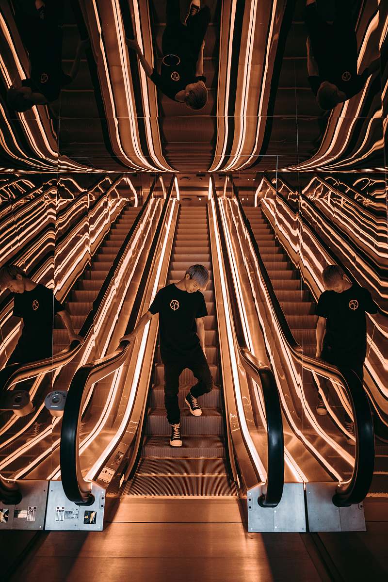 escalator man standing on escalator with string lights menswear
