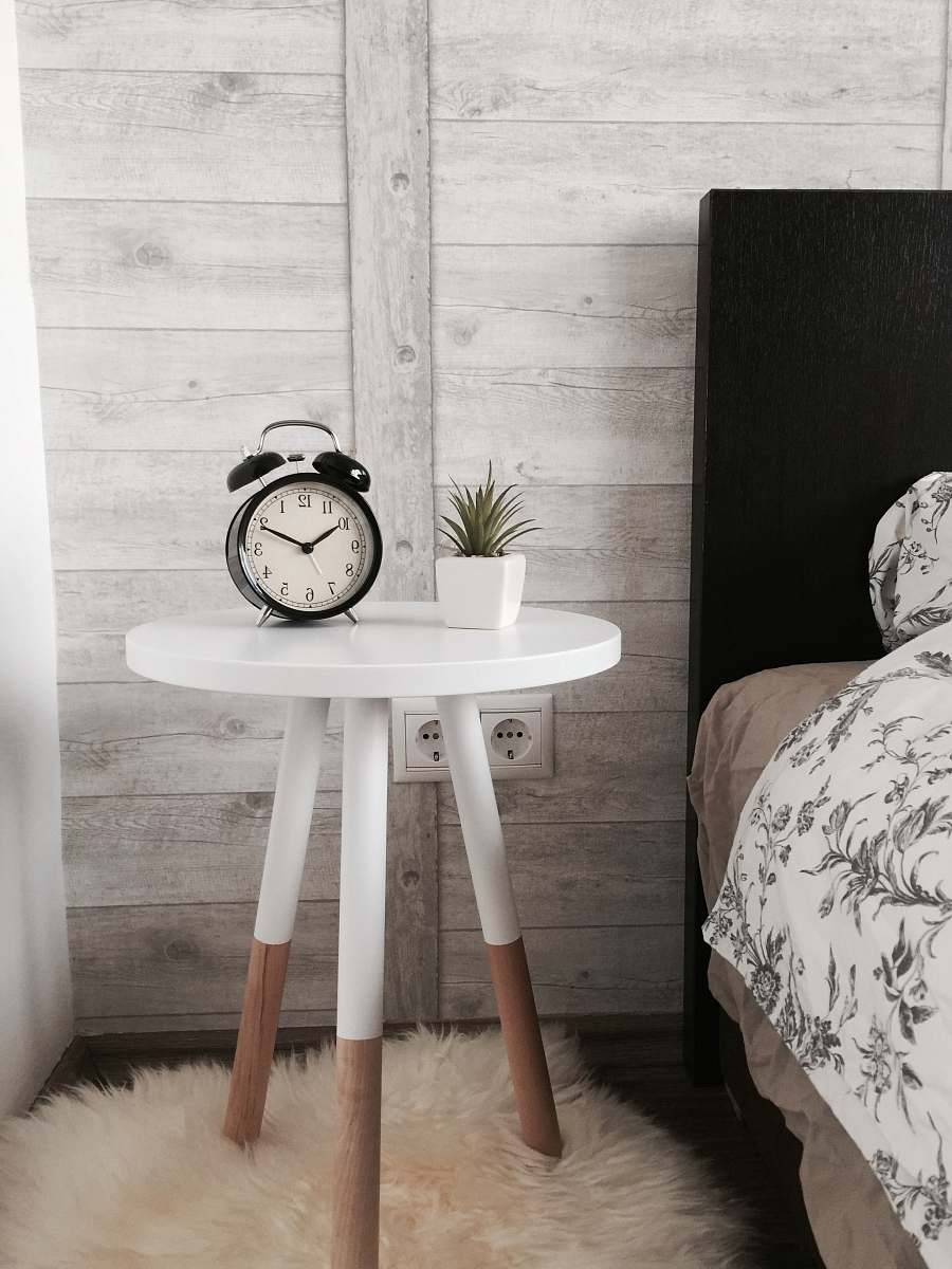 interior black alarm clock at 10:10 on white wooden table near table alarm clock