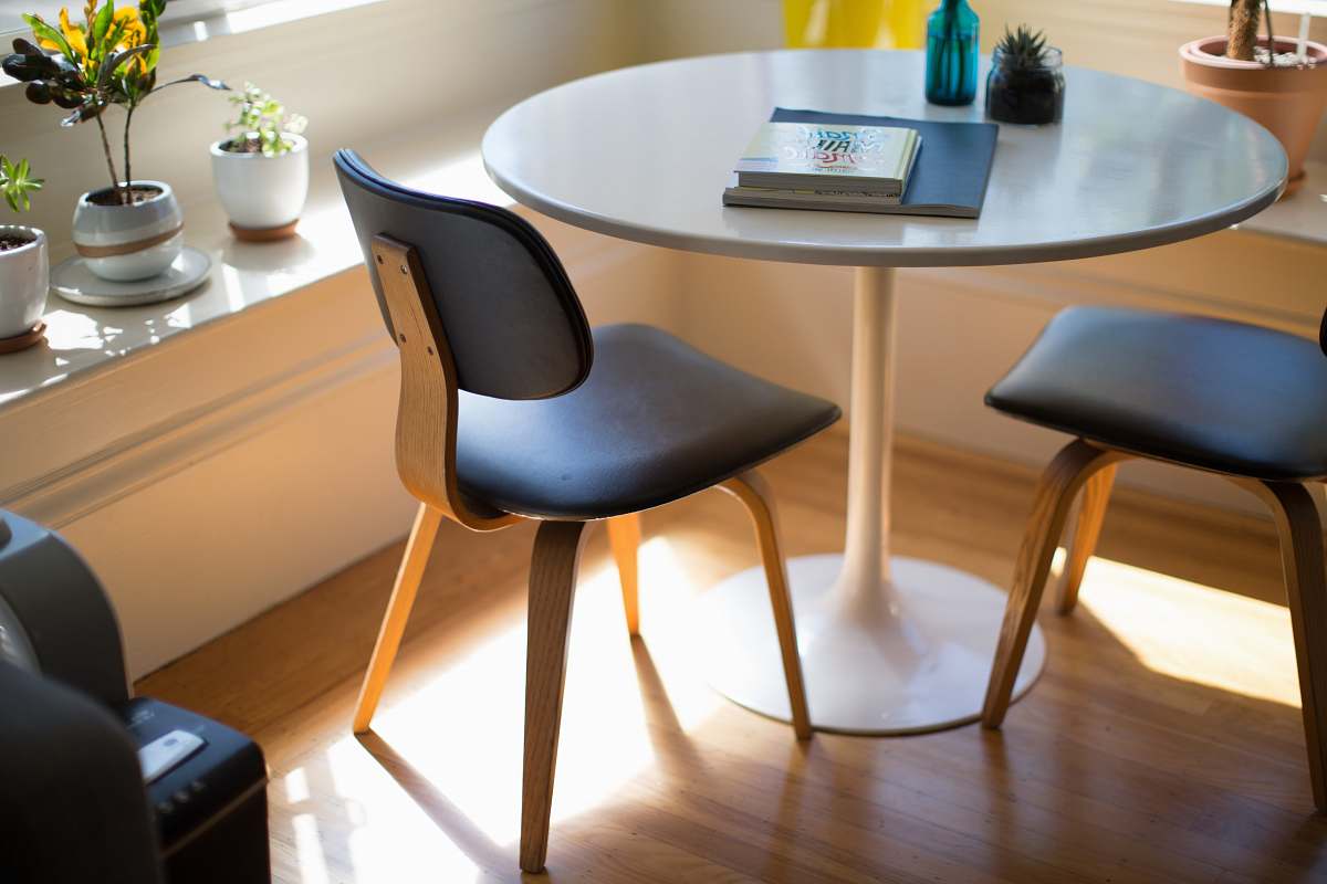 table round white dining table beside two chairs on brown hardwood flooring dining table