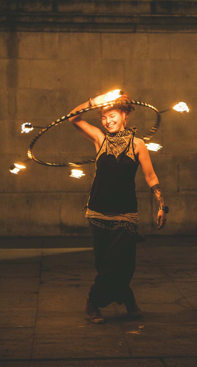 person girl wearing black and gold kameez holding hoop with fire juggling