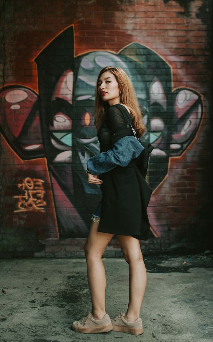 person woman standing near wall with graffiti print during daytime people