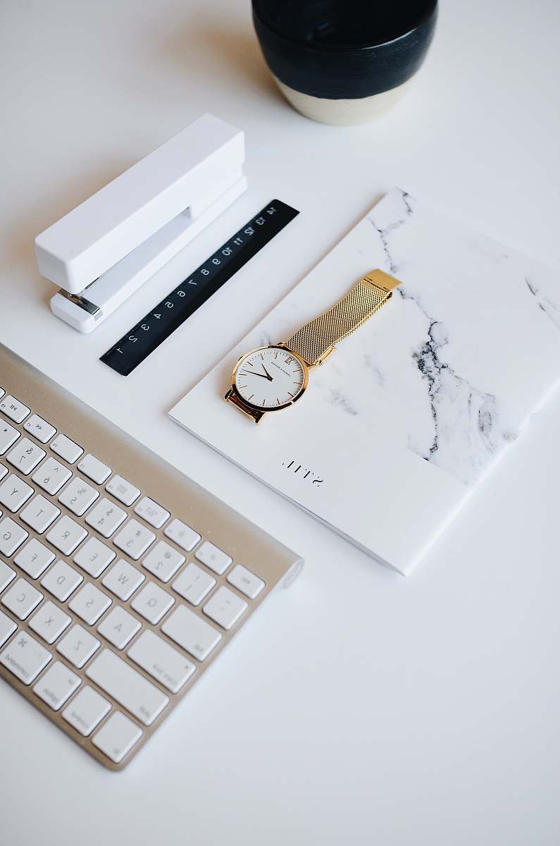 office watch on top of book beside stapler near Apple keyboard design