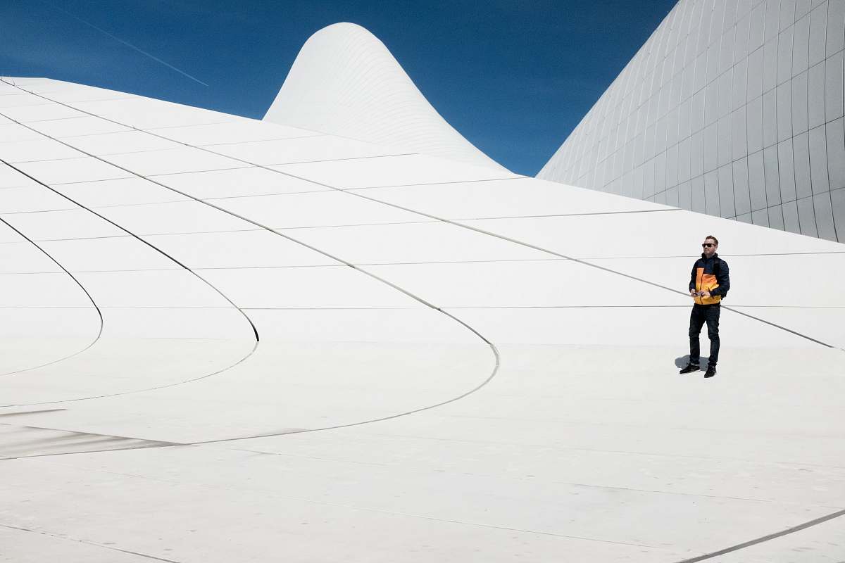 male man in black and orange jacket under blue sky modern
