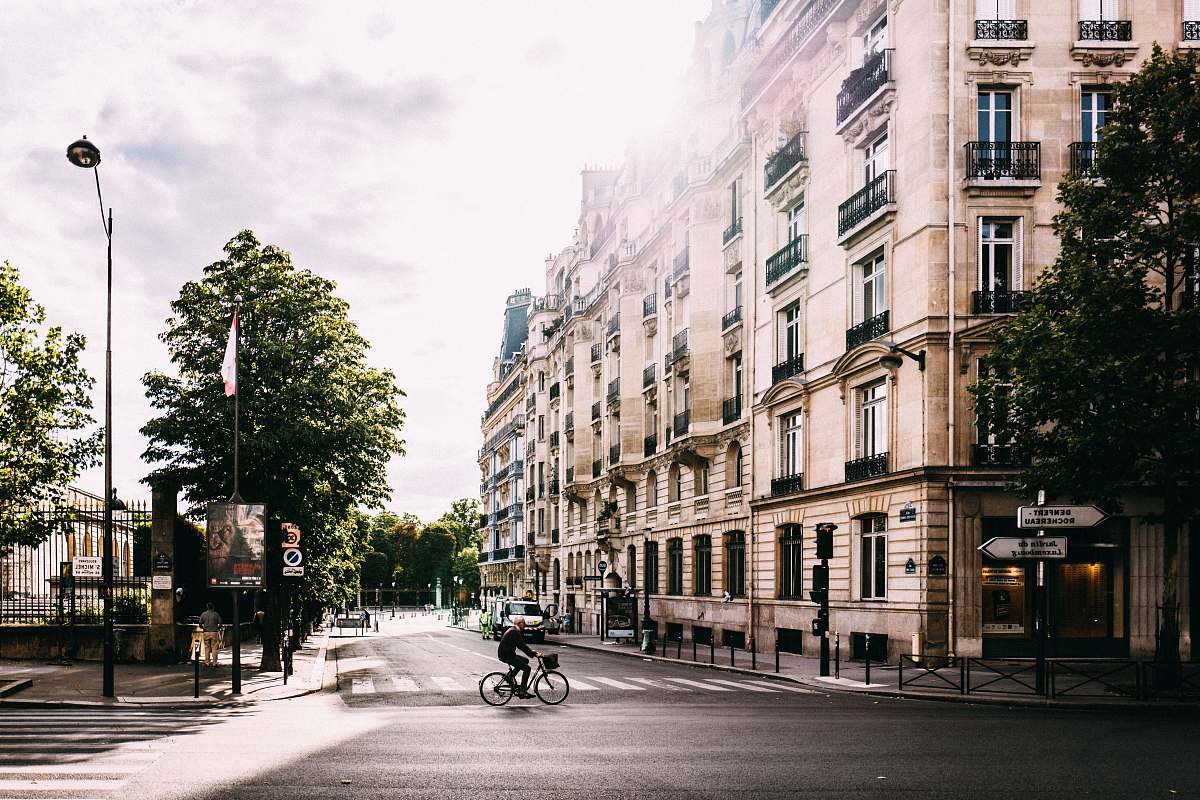 france man riding bike on middle of road near white concrete building building