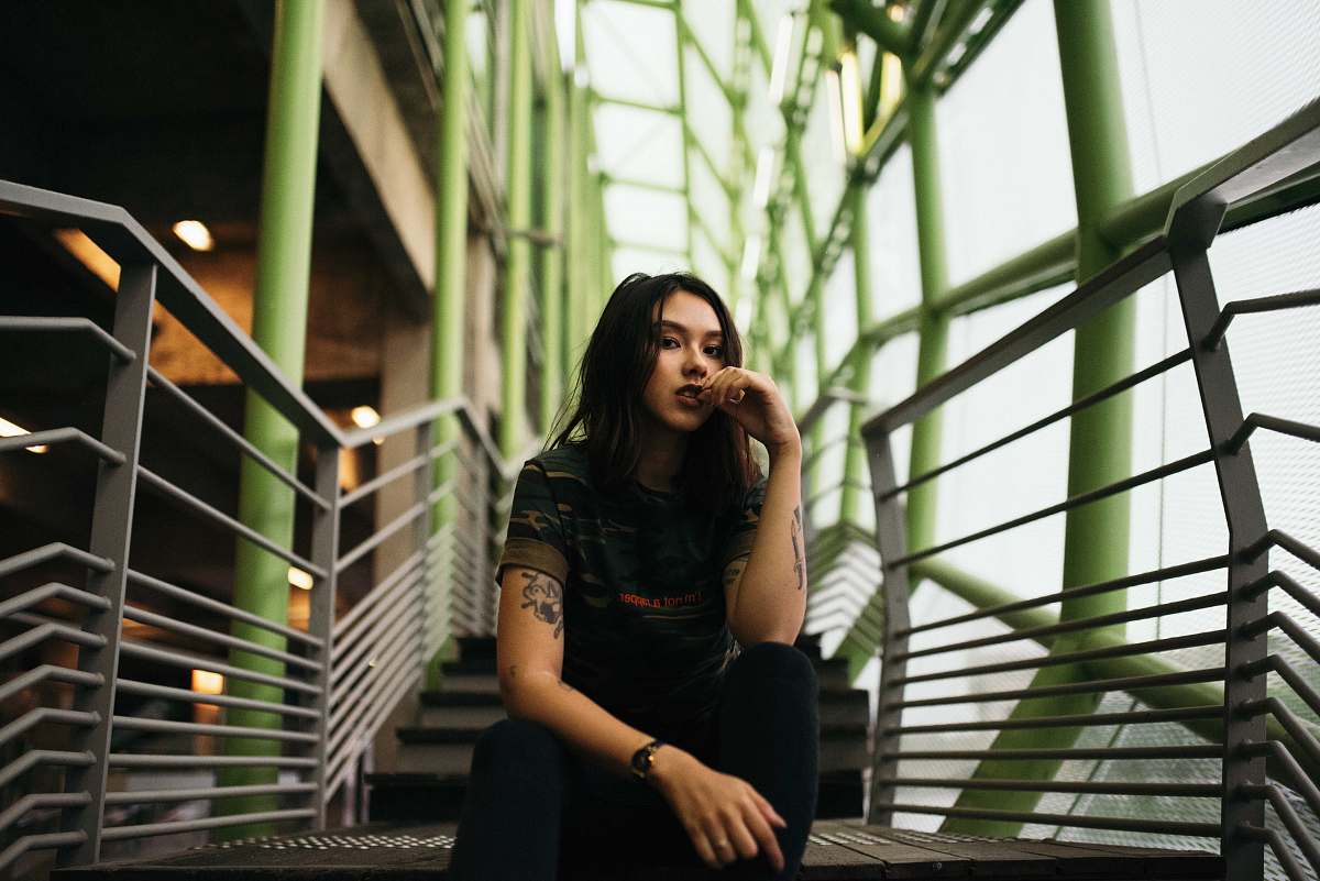 female woman in black crew-neck top sitting on stair woman