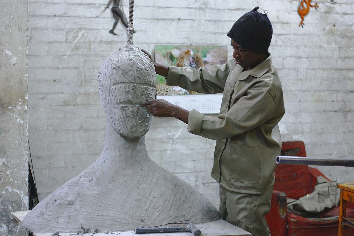 art A sculptor works in his studio sculpting a large white body and head human
