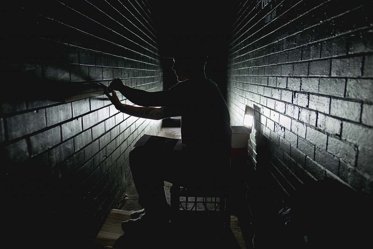 wall person sitting on dark room bricks