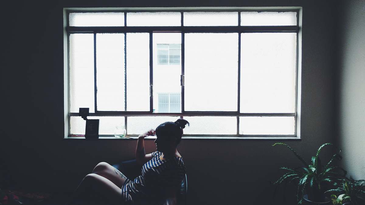 flora woman sitting on chair beside glass window near plant jar