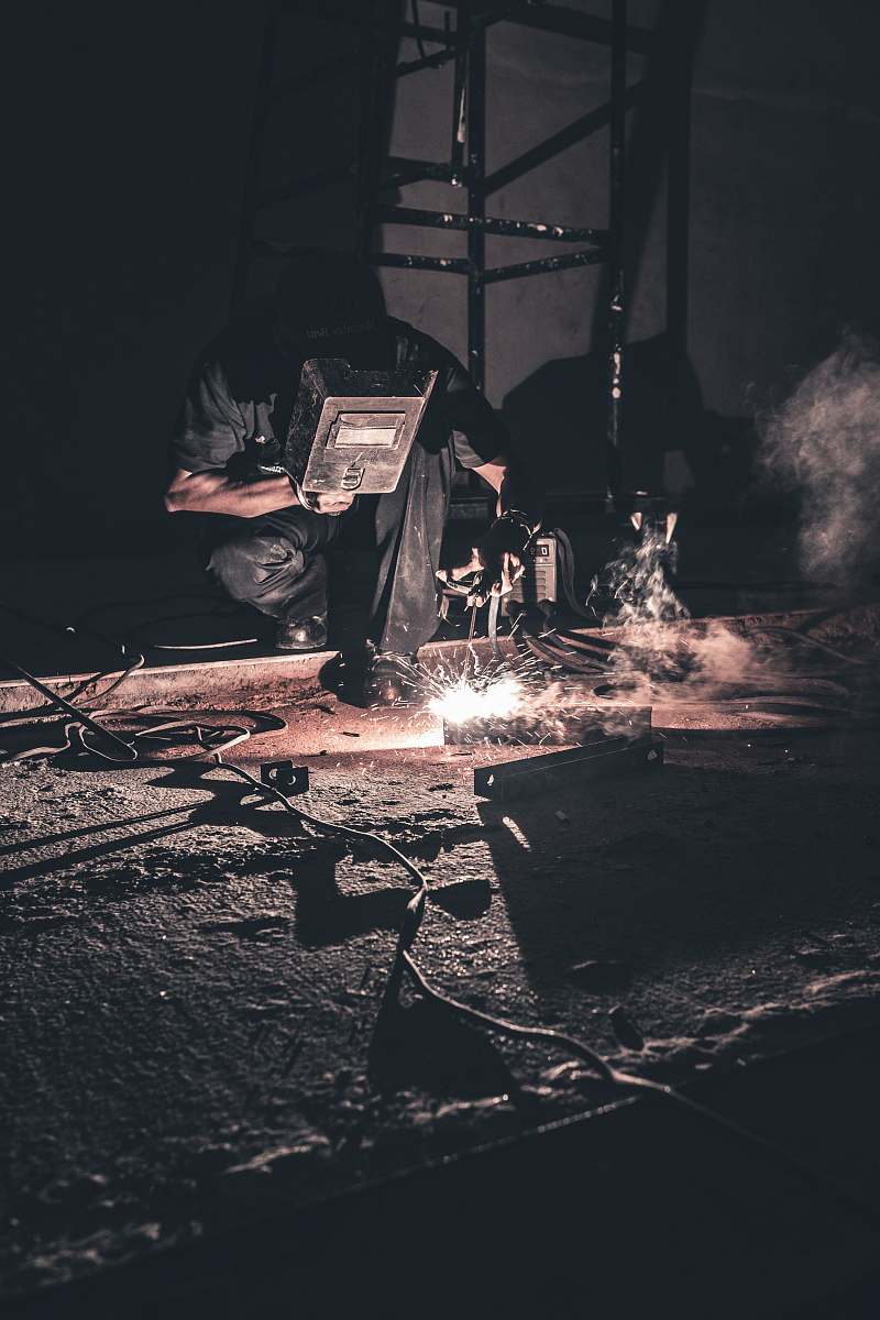 welder man welding black metal rubble