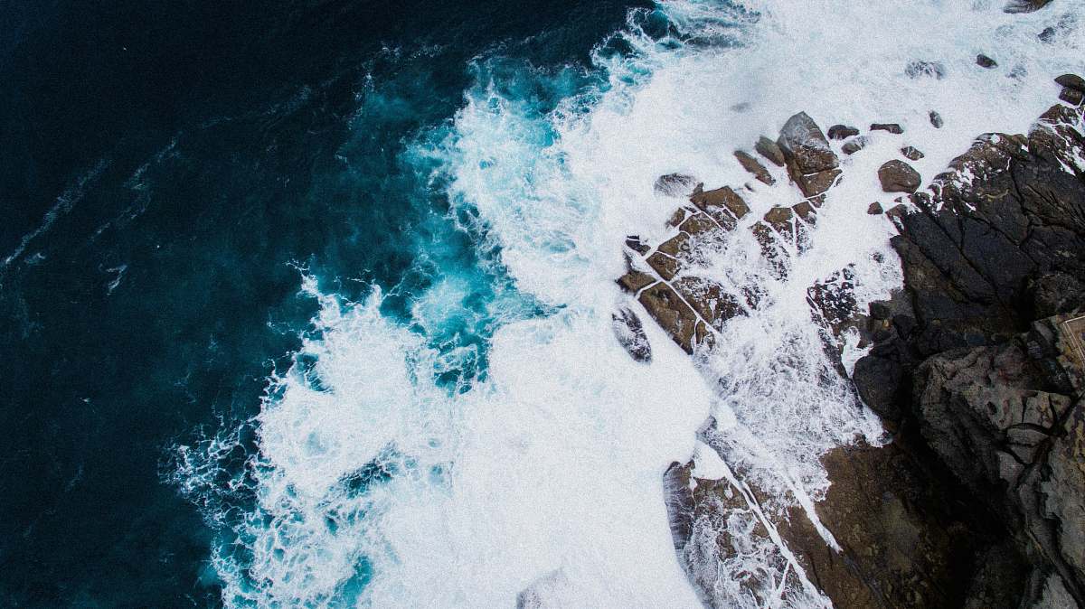 ocean aerial photo of body of water crashing stone rock