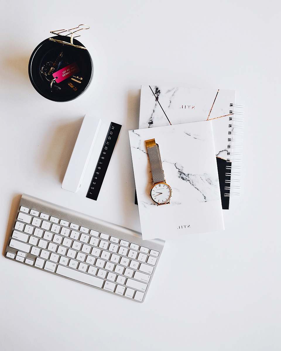 white Apple Magic Keyboard near round gold-colored analog watch with silver-colored mesh band with notebook on white surface photography keyboard