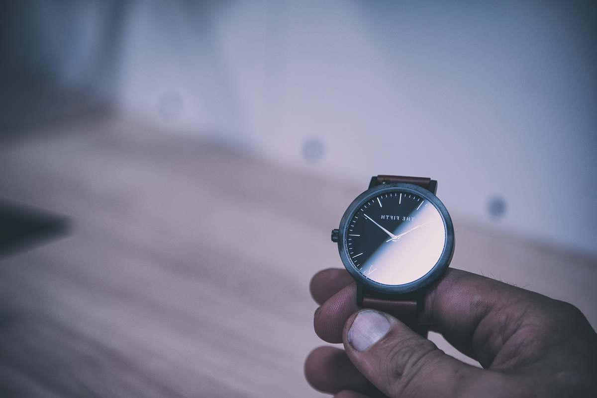 grey person holding analog watch displaying 10:10 time