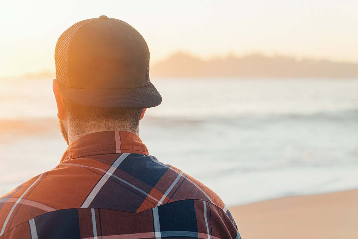 apparel man wearing black, white, brown, and gray plaid dress shirt and black fitted cap clothing