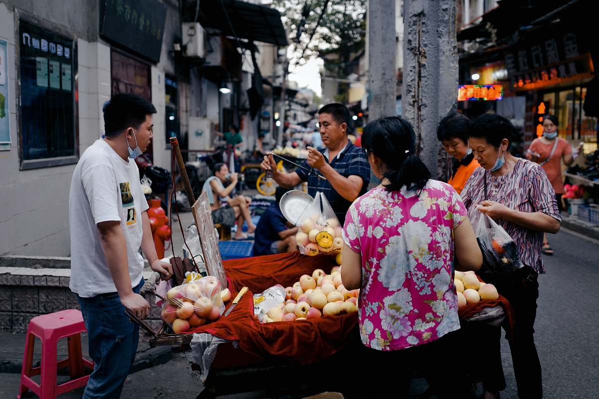 person woman in pink floral dress holding fruit market