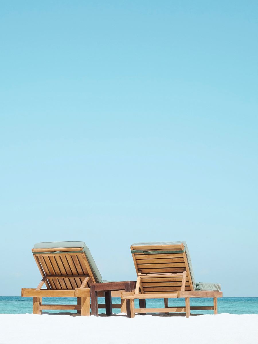 two brown wooden outdoor chaise loungers on beach