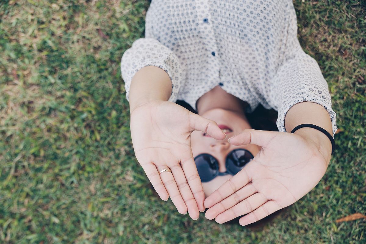 woman lying on grass forming her hands to triangle during daytime