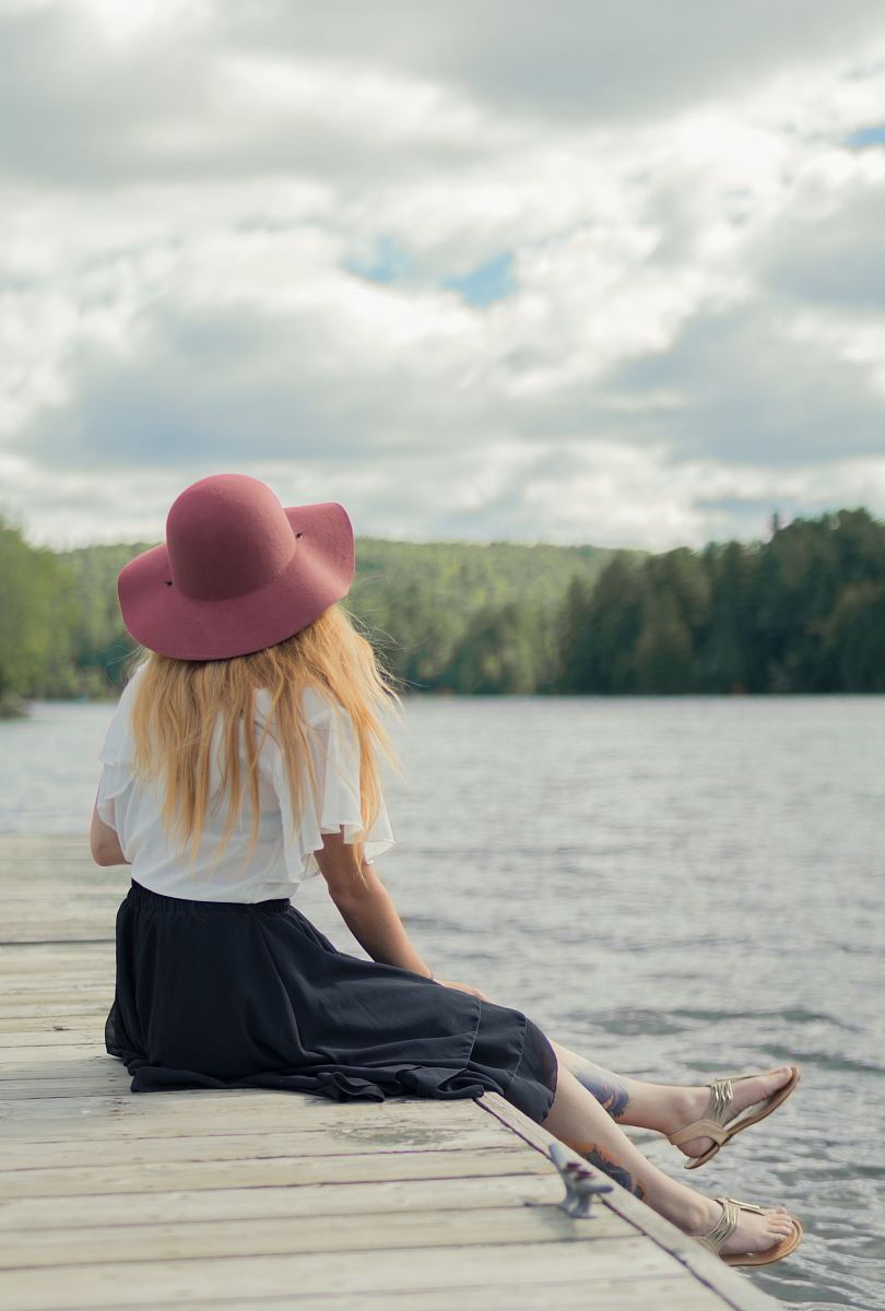 woman sitting on dock under cumulus clouds