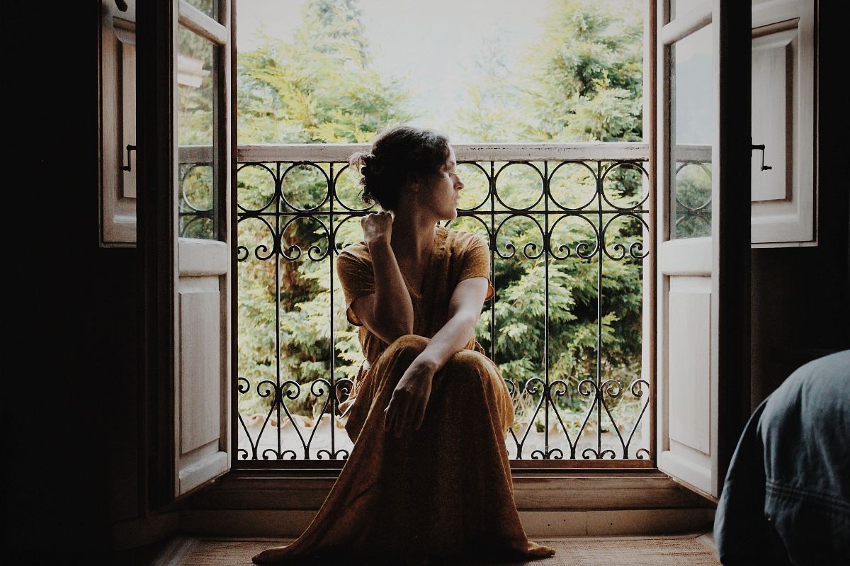 woman sitting on floor near window at daytime