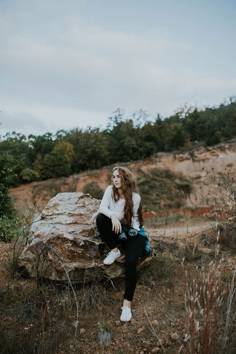 woman sitting on stone boulder outdoor