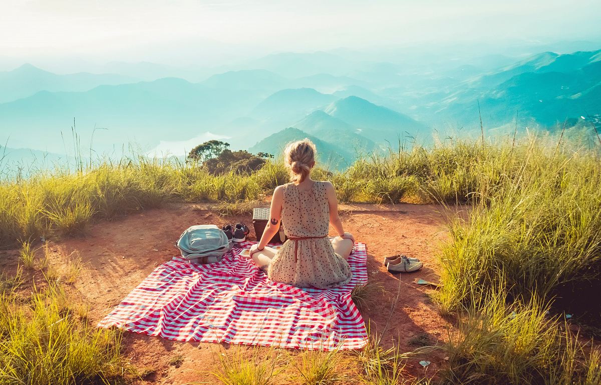 woman wearing gray sleeveless dress sitting on the picnic mat