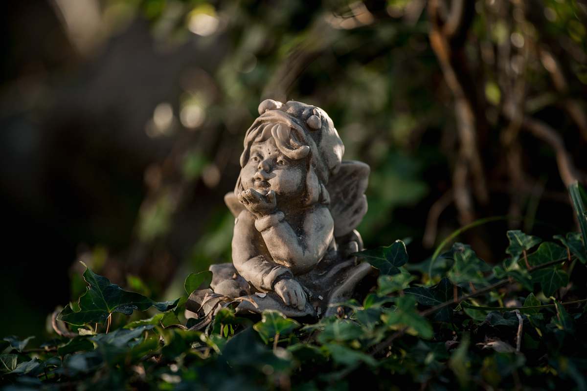 lion girl leaning forward figurine on green leaves mammal