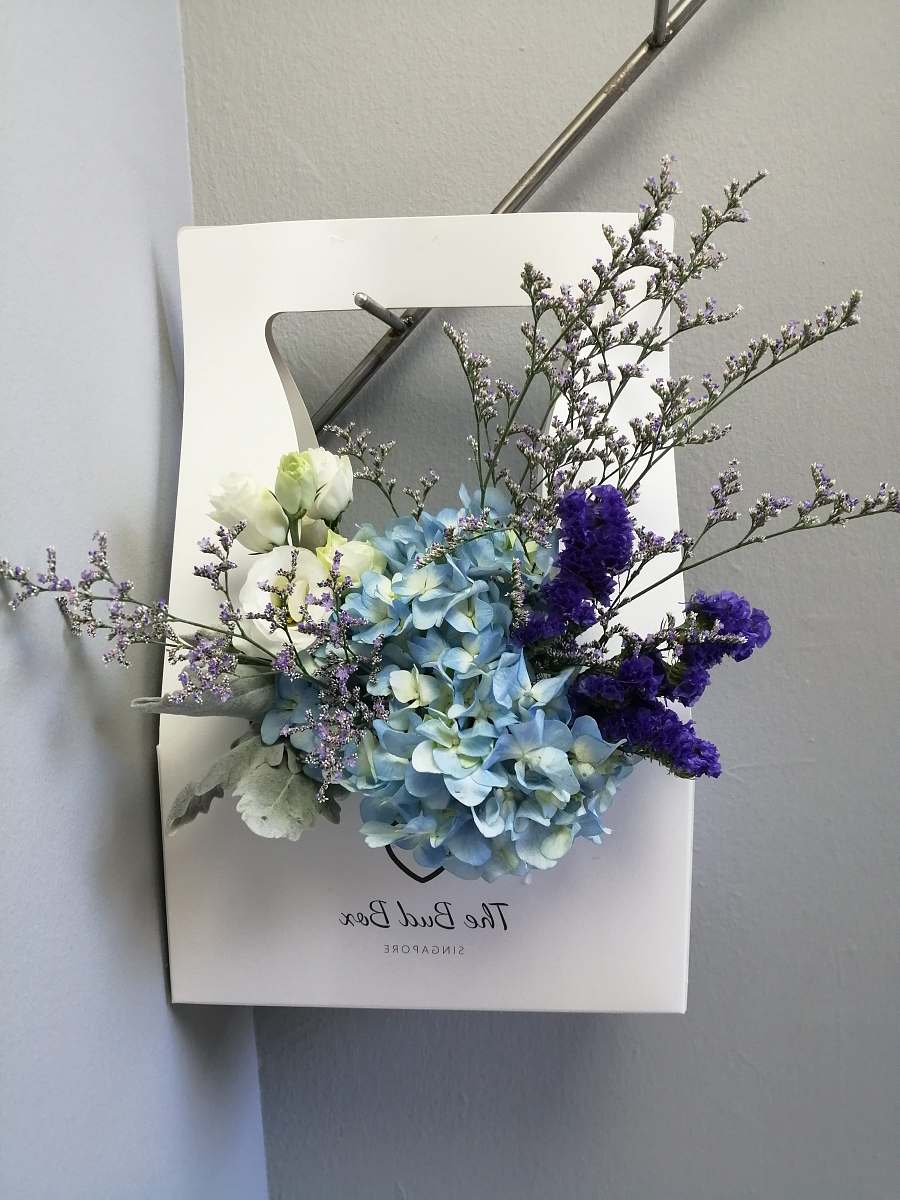 Discover a stunning floral arrangement featuring vibrant plants artfully arranged in a pristine white box. Set against a minimalist wall backdrop, this composition exudes elegance and sophistication, making it perfect for interior design projects, event decor, or promotional materials for florists. The clean lines and contrasting colors create a captivating visual that can enhance any space.