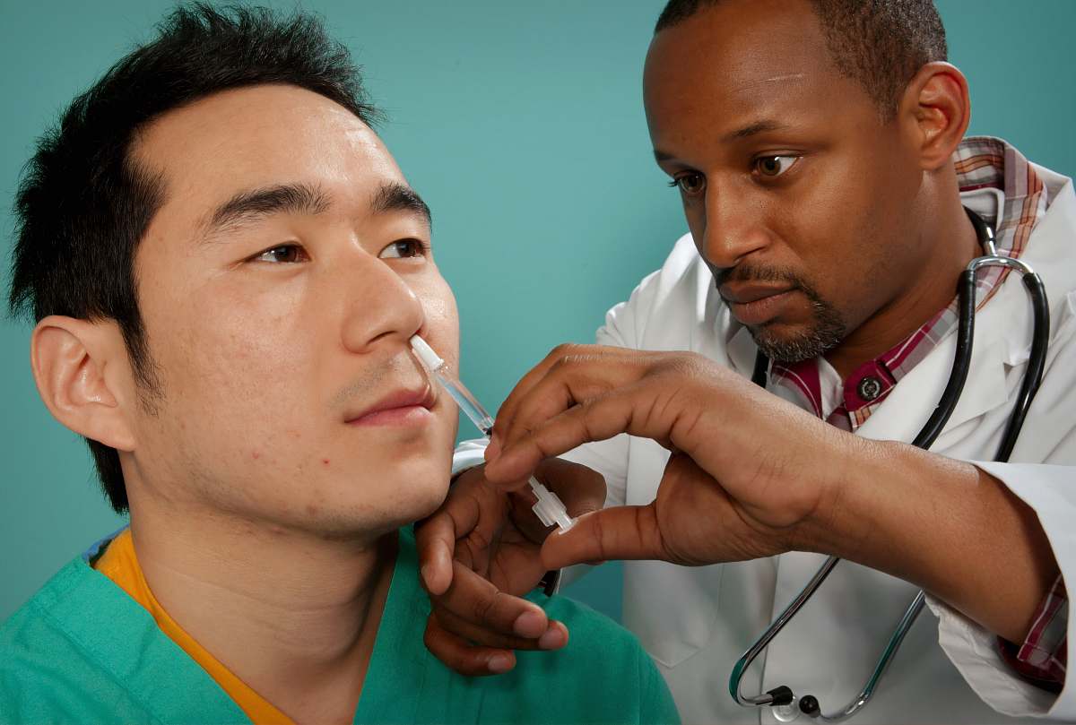 human doctor suctioning on man's nose patient