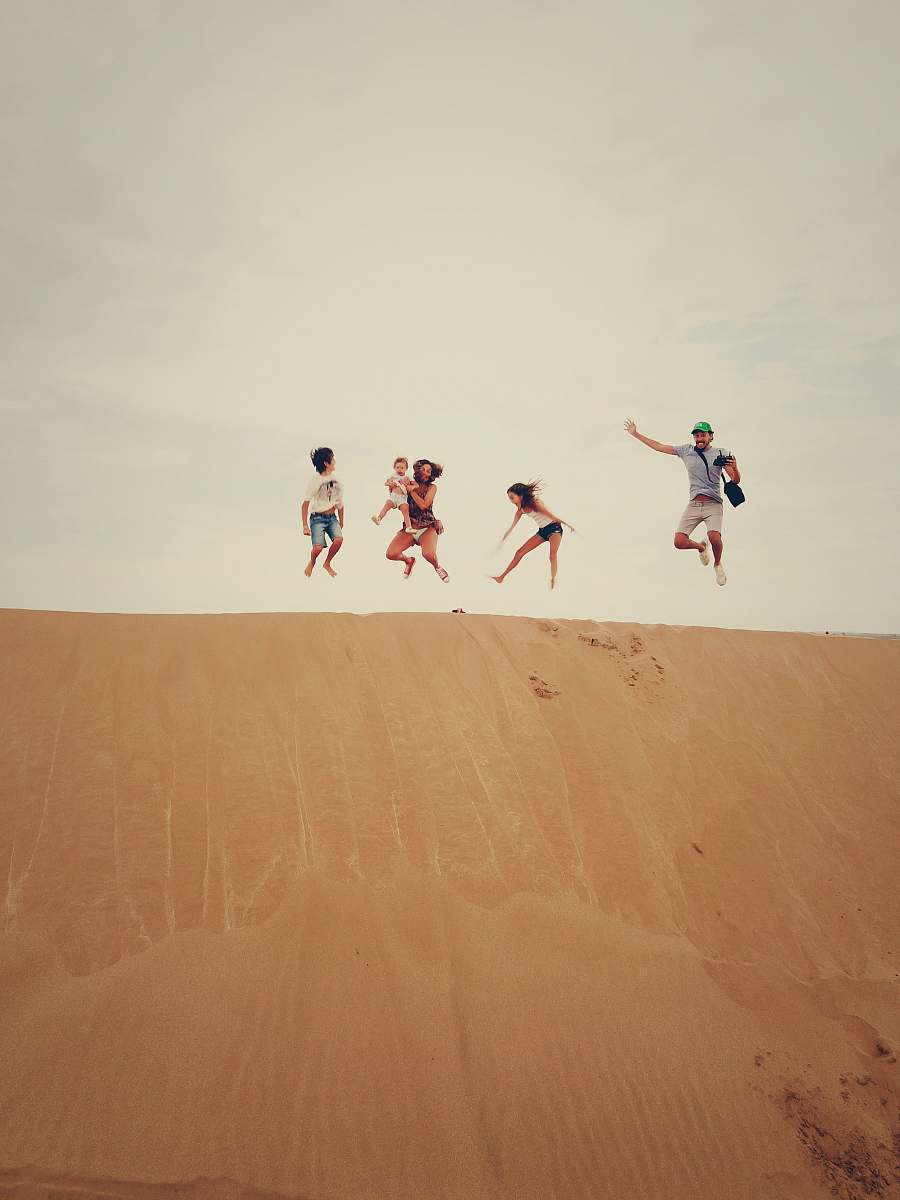 dune people jumping on sand sand